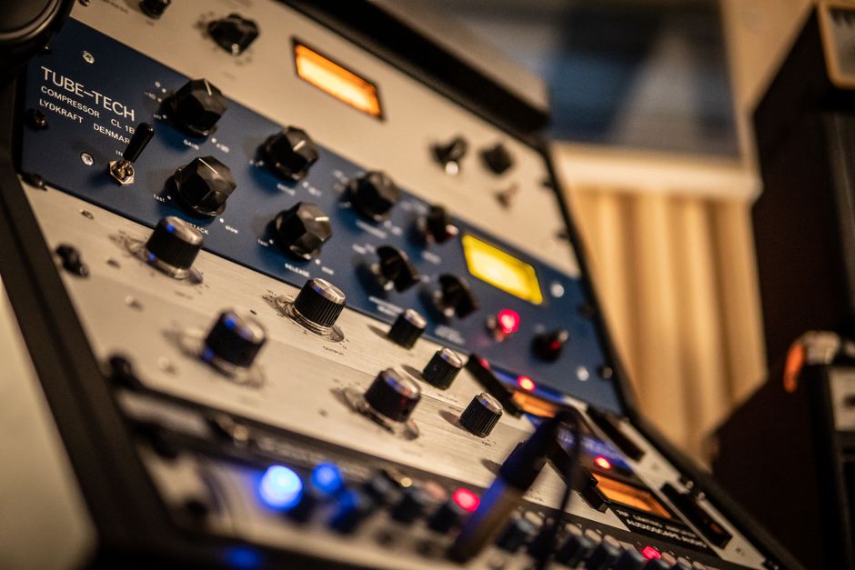 Detailed view of knobs on a Tube-Tech audio compressor in a studio setting.