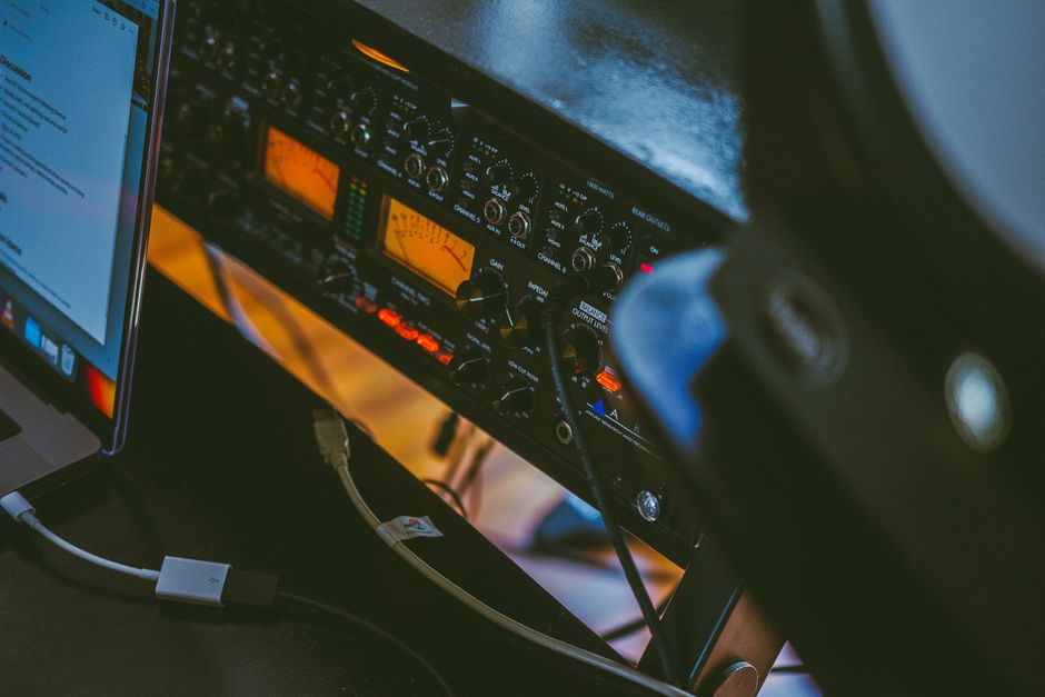 Close-up of a professional audio setup with an amplifier and a connected laptop in a workspace.